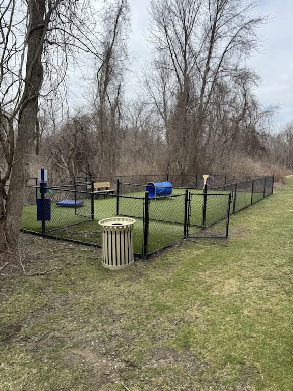 A fenced area with a blue object and a trash can.
