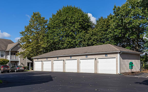 A large garage with four doors is situated in a parking lot.