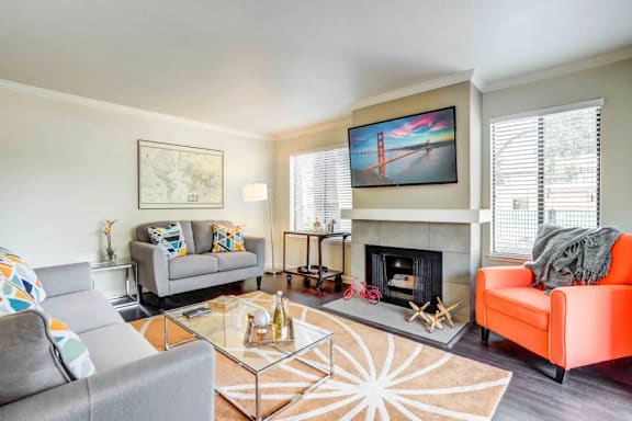 A living room with a fireplace, a couch, a chair, a coffee table, and a painting on the wall.