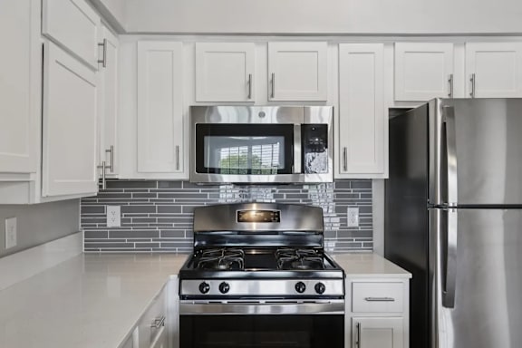 A modern kitchen with a stove, microwave, and refrigerator.