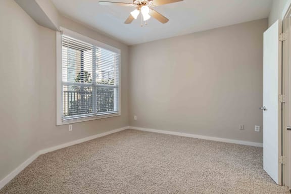 A room with a ceiling fan and a window with blinds.