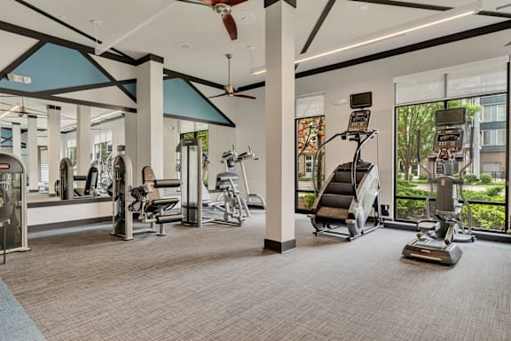 A gym with a variety of equipment including treadmills, stationary bikes, and elliptical machines.