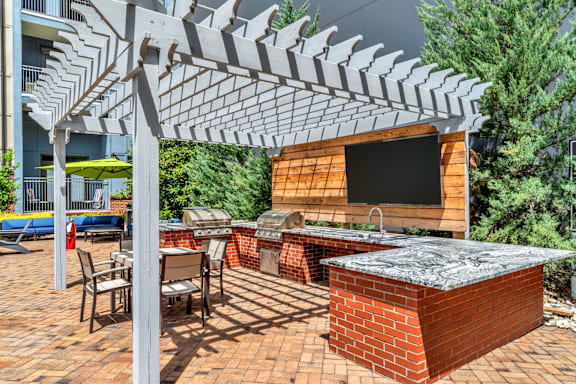 A patio with a table and chairs under a white pergola.