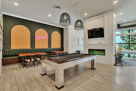 A room with a pool table and a bar area.