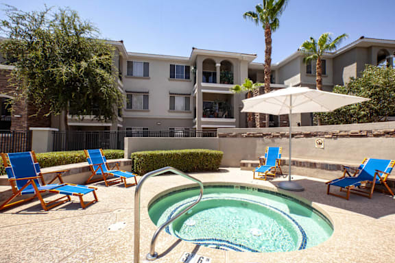A pool surrounded by chairs and an umbrella.