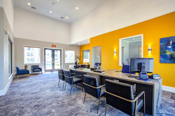 A room with a desk and chairs with a yellow wall.