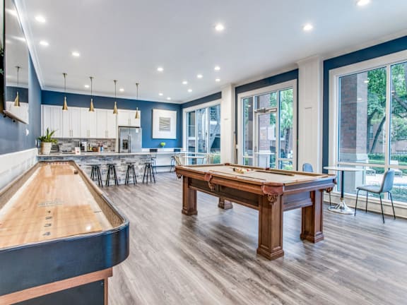 A pool table is in the middle of a room with a long table and chairs.