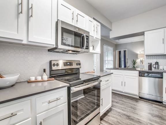 A modern kitchen with white cabinets and stainless steel appliances.