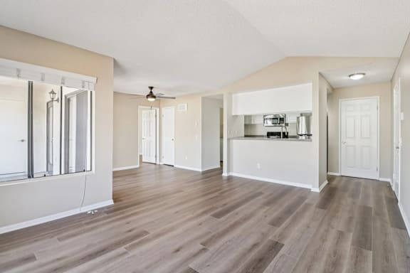 A spacious room with wooden flooring and a ceiling fan.