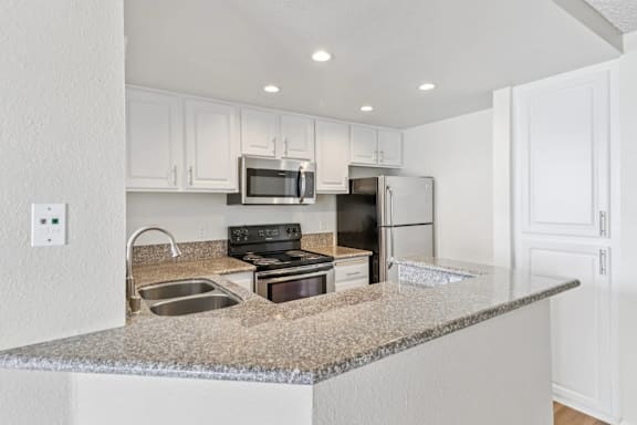 A kitchen with granite countertops and stainless steel appliances.