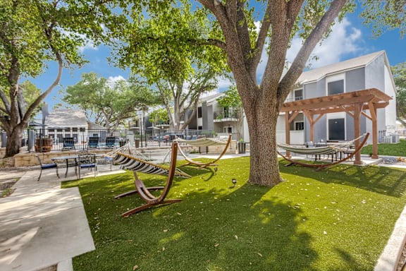 A park with a bench and a tree in front of a building.