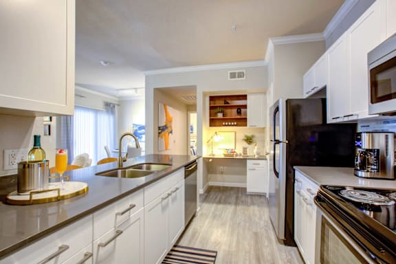 A modern kitchen with white cabinets and stainless steel appliances.