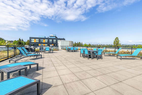 A sunny day at the park with blue seating and a building in the background.