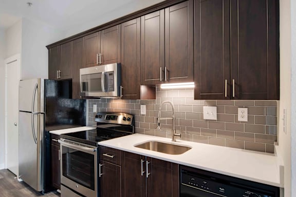 A kitchen with dark brown cabinets and stainless steel appliances.