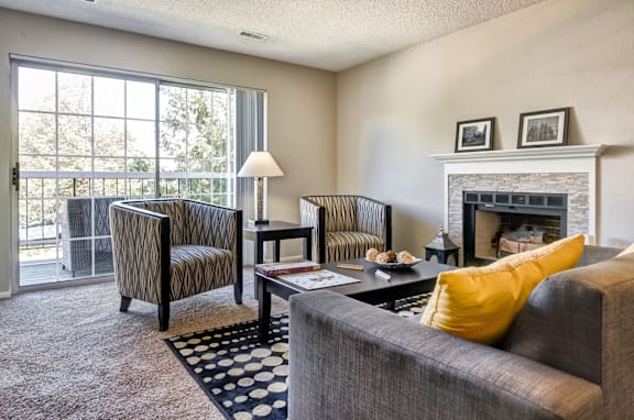 A living room with a grey couch, a chair, a coffee table, and a fireplace.