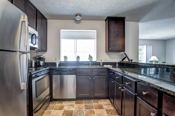 A kitchen with black cabinets and a stainless steel refrigerator.