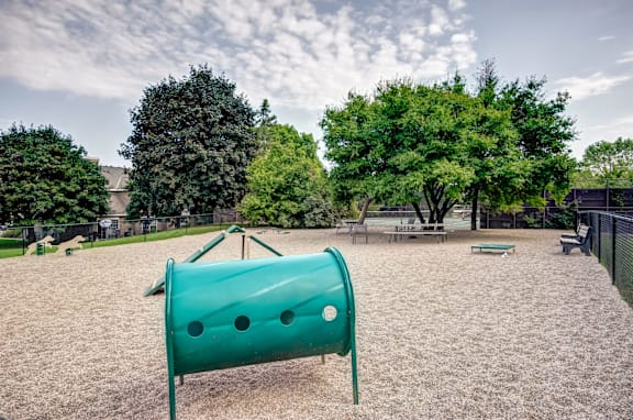 A playground with a green slide and sandy ground.