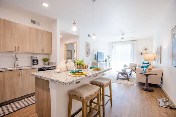 A kitchen with wooden cabinets and a white countertop with a breakfast bar.
