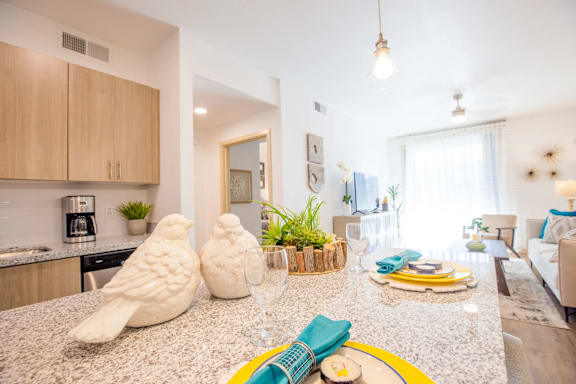 A modern kitchen with a granite countertop and a dining area with a white table and chairs.