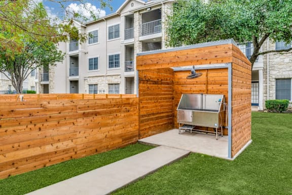 A wooden outdoor kitchen with a grill and sink.