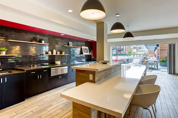 A modern kitchen with a long white counter and black cabinets.