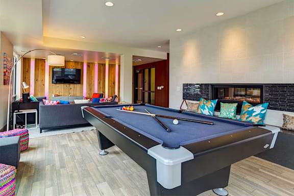 A pool table is in the middle of a room with a TV and a couch.