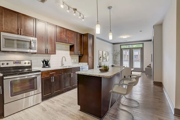 A modern kitchen with dark wood cabinets and stainless steel appliances.