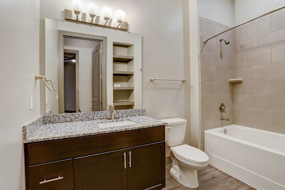 A bathroom with a marble countertop and a white bathtub.