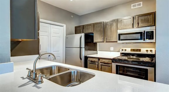 A kitchen with a white counter top and stainless steel appliances.