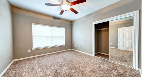 A room with a ceiling fan and a window with blinds.