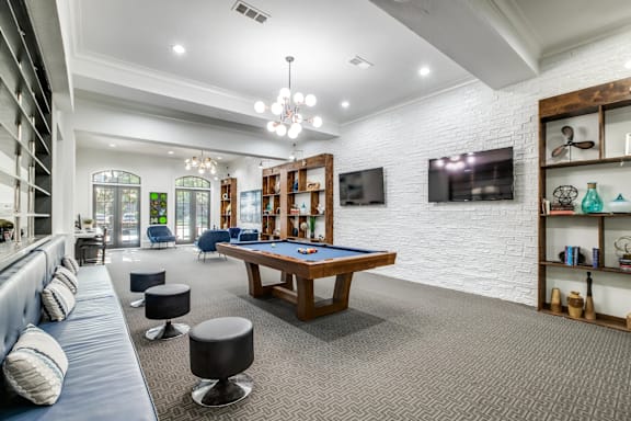 A room with a pool table and a TV mounted on the wall.