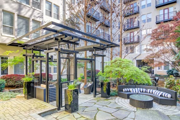 A patio area with a black metal pergola and a stone table.