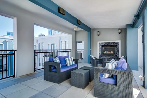 A patio with a fireplace and blue cushions.