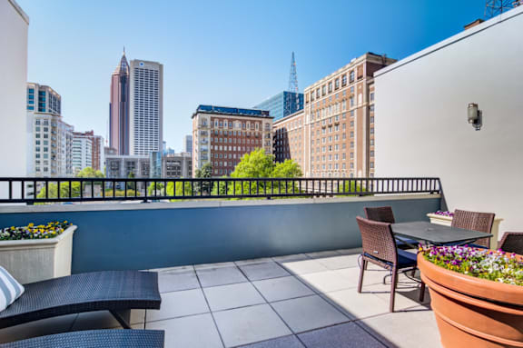 A balcony with a table and chairs overlooking a city skyline.