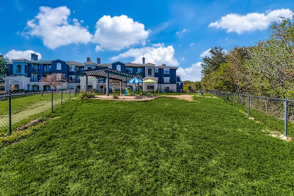 A large grassy area in front of a house with a fence.