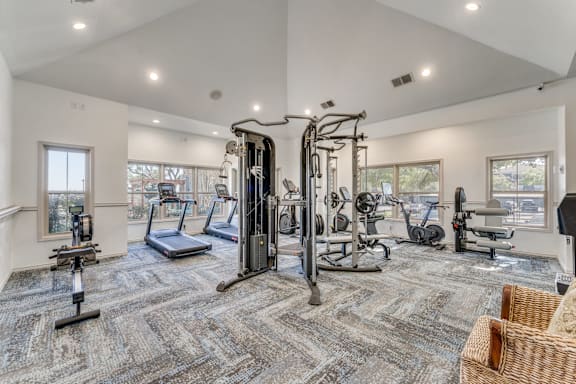 A spacious gym with a variety of equipment including treadmills, elliptical machines, and weight machines.