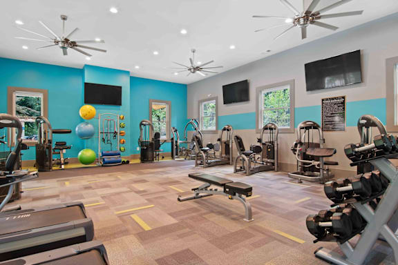 A gym with a variety of equipment including treadmills, weights, and exercise machines.