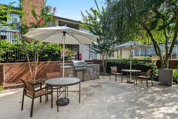 A patio with a table, chairs, and umbrellas.
