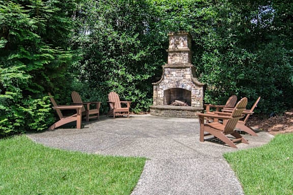 A fireplace is surrounded by chairs in a backyard.
