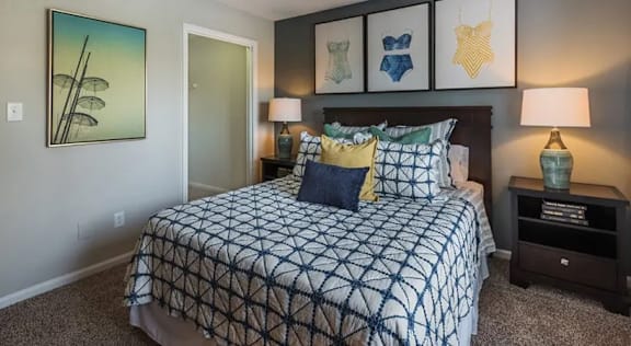 A bedroom with a bed, nightstands, and pictures on the wall.