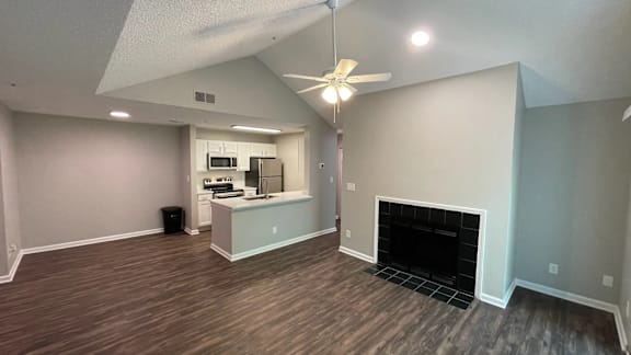 A living room with a fireplace and a kitchen in the background.