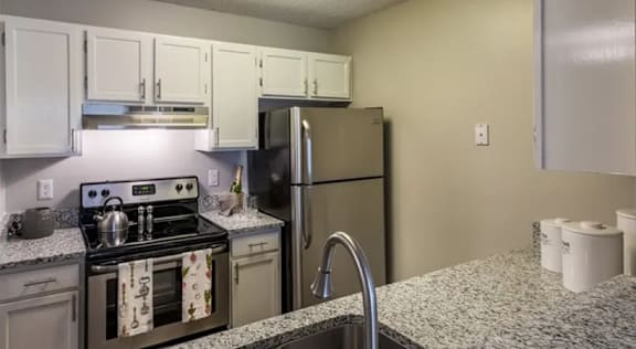 A kitchen with a stove, refrigerator, and cabinets.