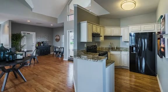 A kitchen with a black fridge and a white island.