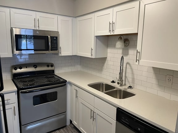 A kitchen with white cabinets and a black stove top oven.