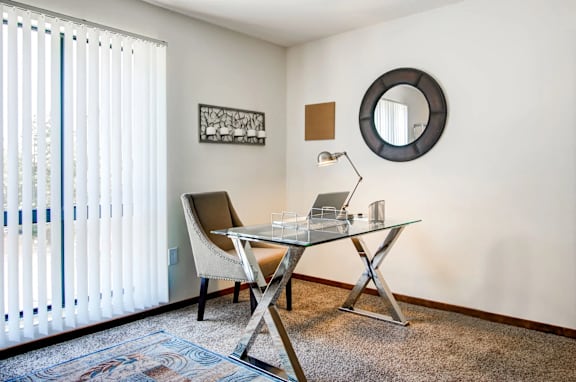 A room with a desk and chair and a round mirror on the wall.