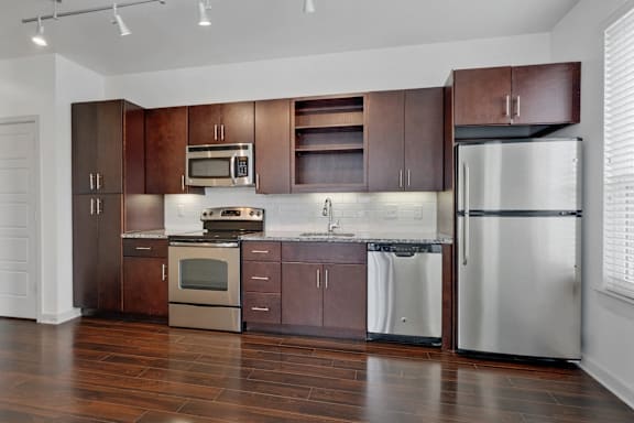 A modern kitchen with dark wood cabinets and stainless steel appliances.
