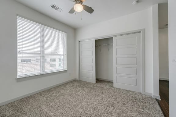 A room with a ceiling fan and a window with blinds.