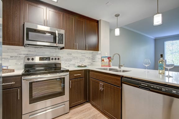 A modern kitchen with dark wood cabinets and stainless steel appliances.