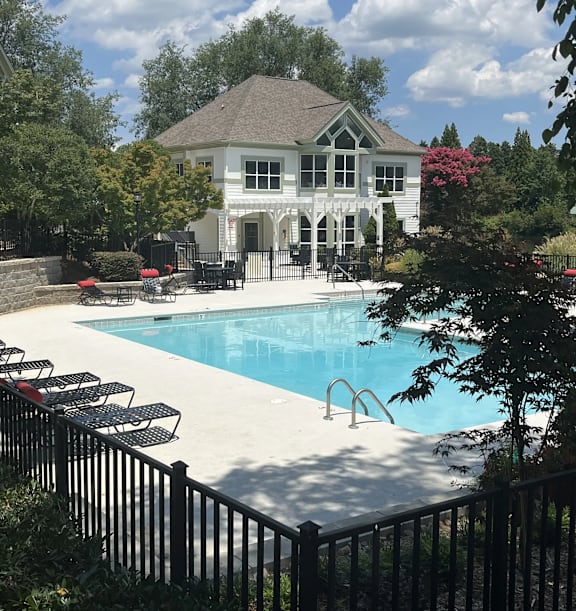 A pool with a black fence and a house in the background.