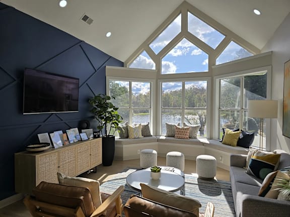 A living room with a large window and a TV mounted on the wall.